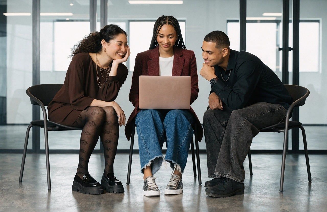 Three colleagues working together around a laptop
